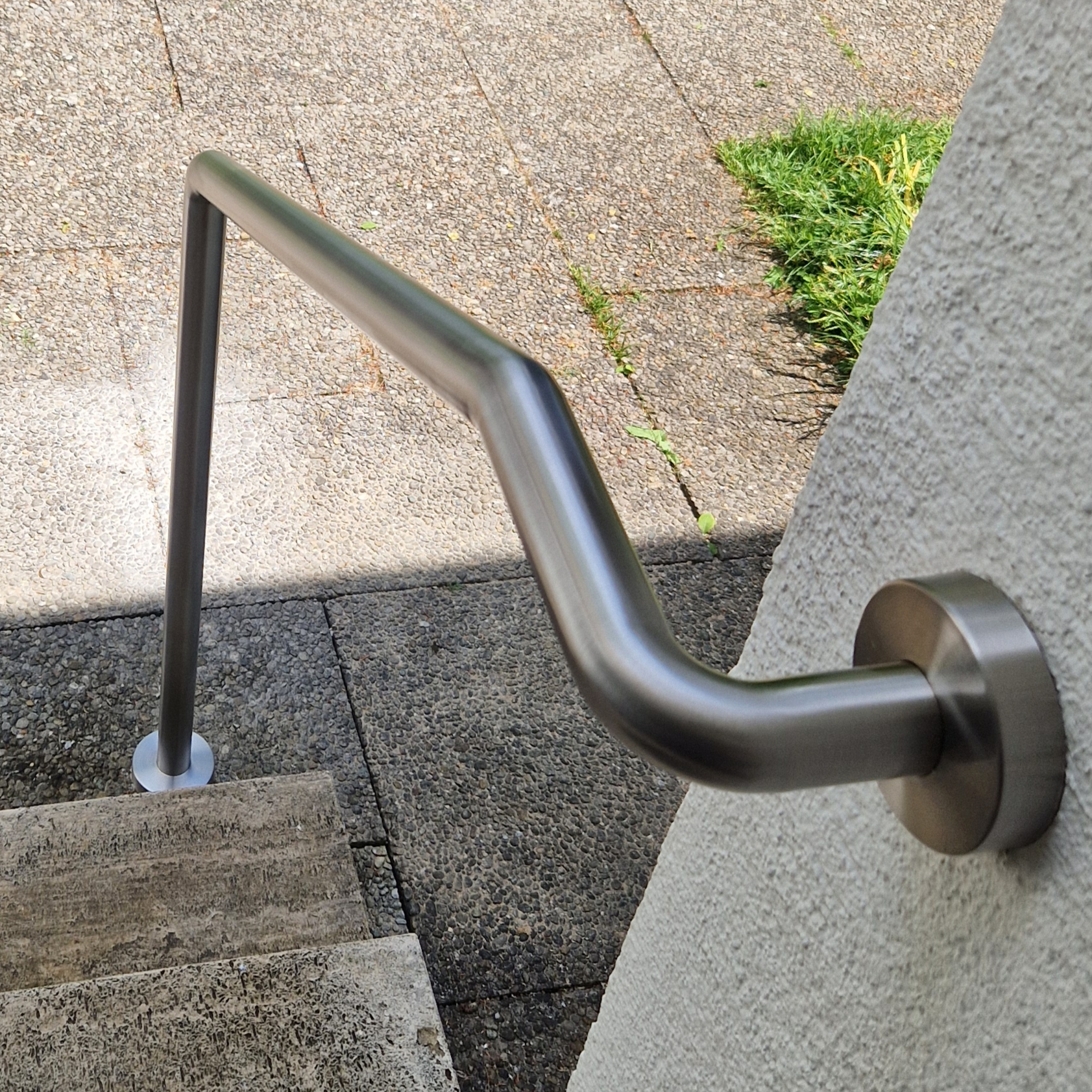 Edelstahl Handlauf um für sicheren Halt auf einer kleinen Treppe vor einer Eingangstür zu Sorgen